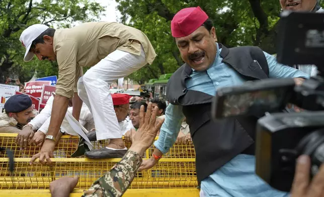 Lawmakers from various opposition jump over a police barricade during a protest calling for the rollback of a controversial revision of the voter list in one of the country’s poorest states where key elections are scheduled in November, in New Delhi, India, Monday, Aug. 11, 2025. (AP Photo/Manish Swarup)