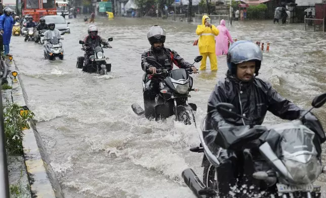 People drive their motorbikes through a waterlogged street during heavy rain Mumbai, India, Monday, Aug. 18, 2025. (AP Photo/Rajanish Kakade)