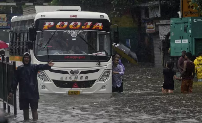 People push a bus through a waterlogged street during a heavy rain in Mumbai, India, Monday, Aug. 18, 2025. (AP Photo/Rajanish Kakade)
