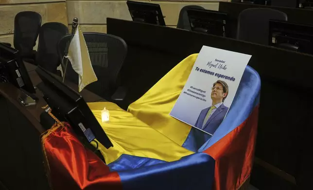 FILE - A leaflet showing Colombian Sen. Miguel Uribe Turbay sits on a Colombian national flag draped over his seat in the congressional chamber in Bogota, Colombia, June 9, 2025. (AP Photo/Ivan Valencia, File)