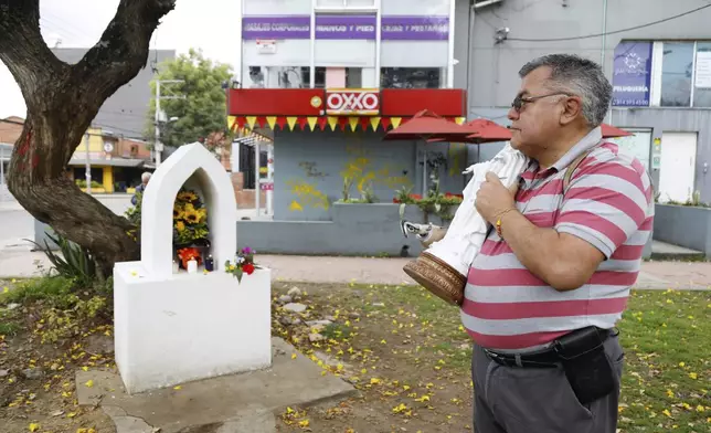 Humberto Celis holds an image of the Virgin at the site where opposition Sen. Miguel Uribe was shot during a political rally more than two months ago, after the announcement of his death, in Bogota, Colombia, Monday, Aug. 11, 2025. (AP Photo/John Wilson Vizcaino)