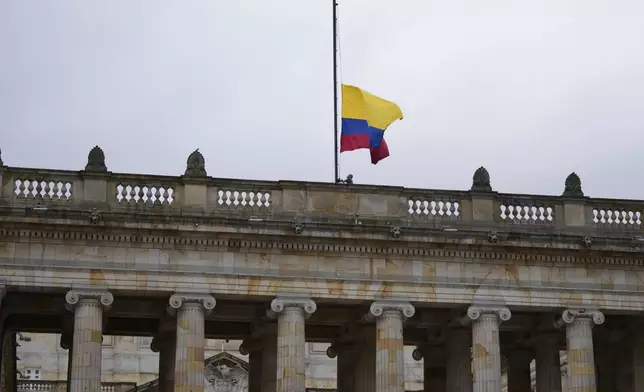 A worker raises the flag to fly at half-staff at Congress in Bogota, Colombia, after the announcement of the death of opposition Sen. Miguel Uribe, more than two months after he was shot during a campaign rally, Monday, Aug. 11, 2025. (AP Photo/Fernando Vergara)