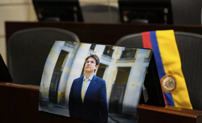 A photo of opposition Sen. Miguel Uribe is placed at his seat in Congress in Bogota, Colombia, Monday, Aug. 11, 2025, after his death more than two months after being shot during a political rally. (AP Photo/Fernando Vergara)