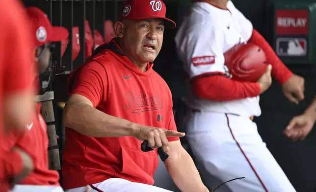 Washington Nationals interim manager Miguel Cairo talks to his coaches in the dugout during the first inning of a baseball game against the Athletics, Thursday, Aug. 7, 2025, in Washington. (AP Photo/John McDonnell)