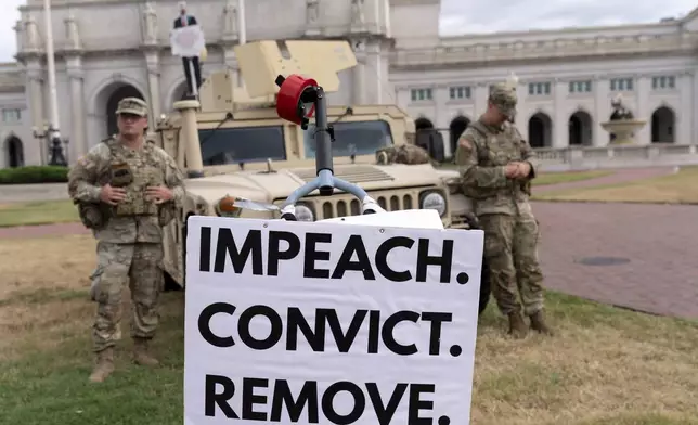 A demonstrator protests next to members of the South Carolina National Guard monitoring the area near Union Station, Sunday, Aug. 24, 2025, in Washington. (AP Photo/Jose Luis Magana)