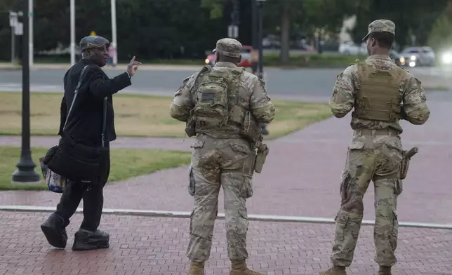 Armed members of the South Carolina National Guard talk with a man while positioned outside of Union Station in Washington, Sunday, Aug. 24, 2025. (AP Photo/Rod Lamkey, Jr.)