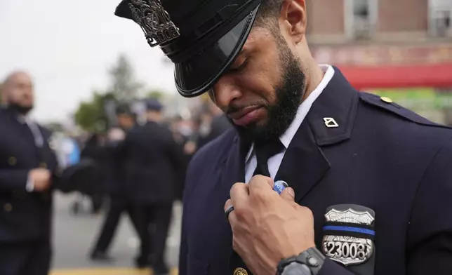 New York Police officer Gregory Matos adjusts a pin on his uniform before attending the funeral for officer Didarul Islam, Thursday, July 31, 2025, in New York. (AP Photo/Angelina Katsanis)