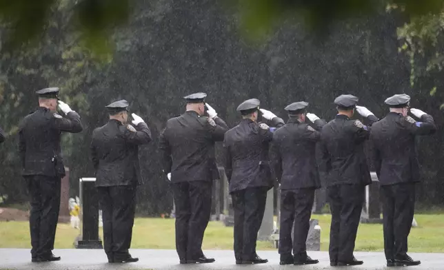 Police officers salute in the rain during the burial of NYPD officer Didarul Islam in Totowa, N.J., Thursday, July 31, 2025. (AP Photo/Seth Wenig)