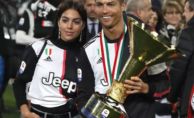 FILE - In this May 19, 2019 file photo, Juventus' Cristiano Ronaldo celebrates with his girlfriend Georgina, left, after winning the Serie A soccer title trophy, at the Allianz Stadium, in Turin, Italy. (AP Photo/Antonio Calanni, File)