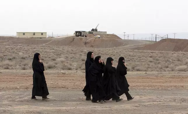 FILE - Iranian women walk past an anti-aircraft gun, at the conclusion of a rally to support Iran's nuclear programs, in front of the Natanz Uranium Enrichment Facility, some 200 miles (322 km) south of the capital Tehran, Iran, March 9, 2006. (AP Photo/Vahid Salemi, File)