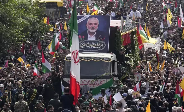 FILE- Iranians follow a truck, center, carrying the coffins of Hamas leader Ismail Haniyeh and his bodyguard who were killed in an assassination blamed on Israel on Wednesday, during their funeral ceremony at Enqelab-e-Eslami (Islamic Revolution) Sq. in Tehran, Iran, Aug. 1, 2024. (AP Photo/Vahid Salemi, file)