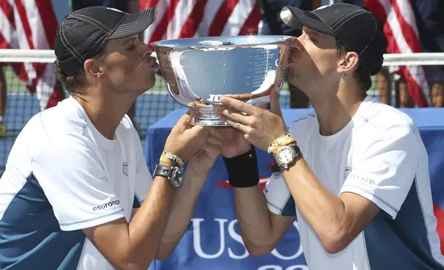 FILE - Bob, left, and Mike Bryan kiss the men's doubles championship trophy after defeating Marc Lopez and Marcel Granollers, of Spain, in the doubles championship match of the 2014 U.S. Open tennis tournament in New York, Sept. 7, 2014. (AP Photo/Mike Groll, File)