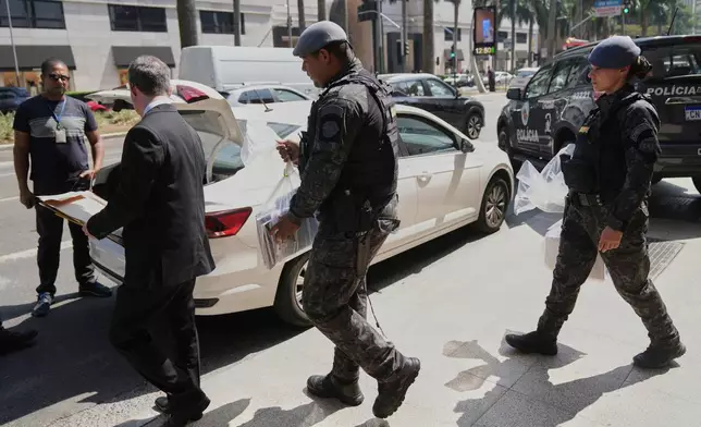 Police officers leave a building with seized documents, during an operation investigating investment funds and the fuel sector, on Avenida Faria Lima, in Sao Paulo, Thursday, Aug. 28, 2025. (AP Photo/Andre Penner)