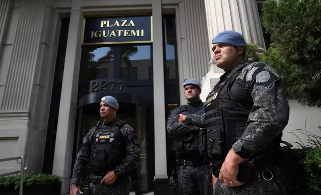Police stand guard in front of a building during an operation investigating investment funds and the fuel sector, on Avenida Faria Lima, in Sao Paulo, Thursday, Aug. 28, 2025. (AP Photo/Andre Penner)