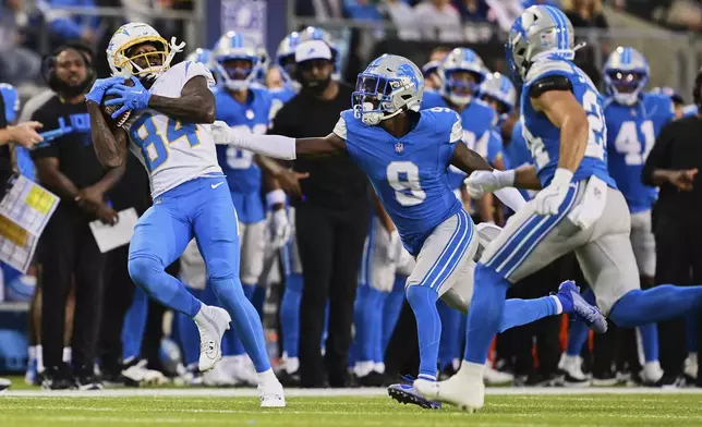 Los Angeles Chargers wide receiver KeAndre Lambert-Smith (84) catches a pass in front of Detroit Lions cornerback Ennis Rakestraw Jr. (9) and Loren Strickland, right, in the first half of the Pro Football Hall of Fame NFL preseason game Thursday, July 31, 2025, in Canton, Ohio. (AP Photo/David Dermer)