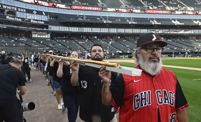 A 50-foot hot dog is paraded around before a baseball game between the Chicago White Sox and the Cleveland Guardians at Rate Field, Saturday, Aug. 9, 2025, in Chicago. (AP Photo/Paul Beaty)