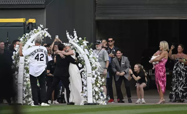 Two lifelong Chicago White Sox fans kiss after exchanging wedding vows during a 60-second wedding officiated by former White Sox player and 1983 rookie of the year Ron Kittle at a baseball game between the White Sox and theCleveland Guardians, Saturday, Aug. 9, 2025, in Chicago. (AP Photo/Paul Beaty)