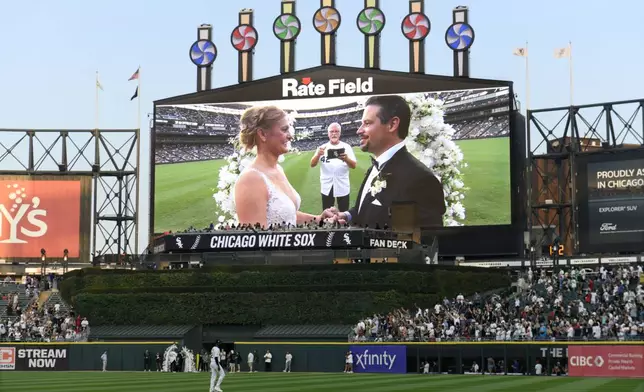 Two lifelong Chicago White Sox fans exchange wedding vows during a 60-second wedding officiated by former White Sox player and 1983 rookie of the year Ron Kittle at a baseball game between the White Sox and the Cleveland Guardians, Saturday, Aug. 9, 2025, in Chicago. (AP Photo/Paul Beaty)
