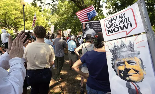 Activists carry signs during a protest against President Donald Trump's federal takeover of policing of the District of Columbia, Saturday, Aug. 16, 2025, in Washington. (AP Photo/Alex Brandon)