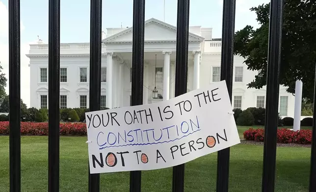 A sign hangs outside the White House as activists protest President Donald Trump's federal takeover of policing of the District of Columbia, Saturday, Aug. 16, 2025, in Washington. (AP Photo/Alex Brandon)