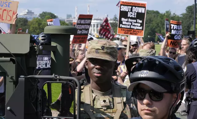 Washington Metropolitan Police officers and military police soldiers with the District of Columbia National Guard watch as activists protest President Donald Trump's federal takeover of policing of the District of Columbia, Saturday, Aug. 16, 2025, in Washington. (AP Photo/Alex Brandon)