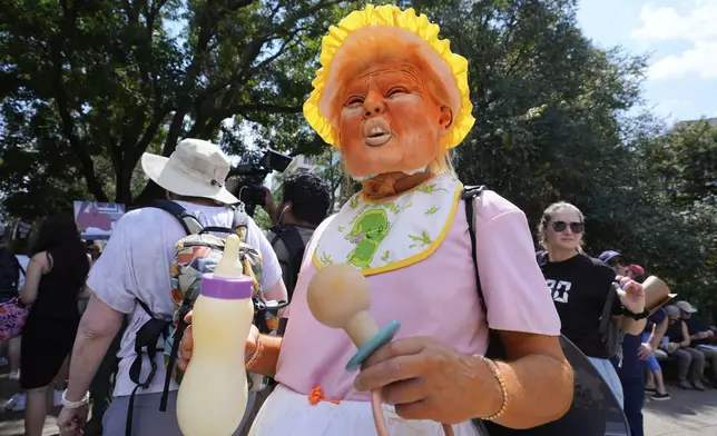 Bob Sledzaus, of Reston, Va., wears a President Donald Trump mask and costume during a protest of Trump's federal takeover of policing of the District of Columbia, Saturday, Aug. 16, 2025, in Washington. (AP Photo/Alex Brandon)