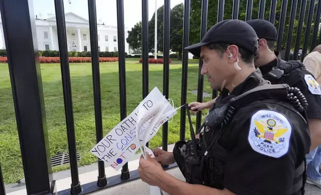 Officers with the Park Police remove signs near the White House as activists protest President Donald Trump's federal takeover of policing of the District of Columbia, Saturday, Aug. 16, 2025, in Washington. (AP Photo/Alex Brandon)