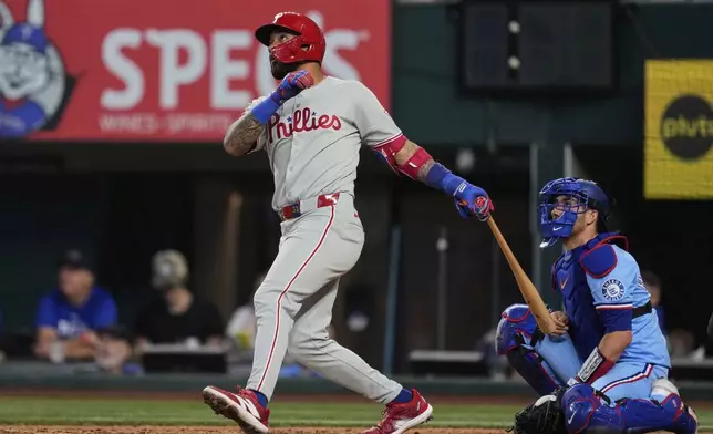 Philadelphia Phillies' Edmundo Sosa, left, follows through on a solo home run swing as Texas Rangers catcher Kyle Higashioka, right, looks on in the fifth inning of a baseball game Sunday, Aug. 10, 2025, in Arlington, Texas. (AP Photo/Tony Gutierrez)