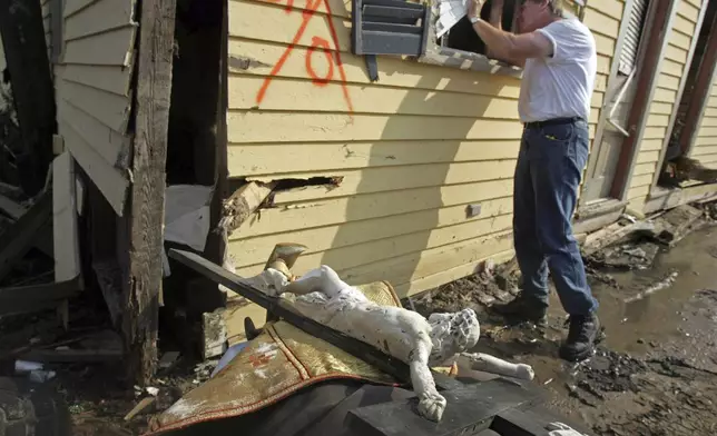 FILE - Father Dennis Carver of St. Paul's Catholic Church looks inside the Damascus House, which was built in 1870, and part of his church in Pass Christian, Miss., Sept. 5, 2005. (AP Photo/John Bazemore, File)