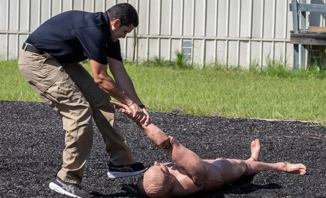 An Immigration and Customs Enforcement (ICE) instructor demonstrates getting a 170 lb. dummy into a position to be handcuffed on the agility course at the Federal Law Enforcement Training Centers (FLETC) in Brunswick, Ga. on Thursday, Aug. 21, 2025. (AP Photo/Fran Ruchalski)
