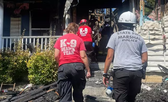 This photo provided by the Office of the State Fire Marshal shows a K-9 Search team and State Fire Marshal police working on site at a house that burned in a deadly fire in Waldorf, Md., Sunday, Aug. 10, 2025. (Office of the State Fire Marshal via AP)