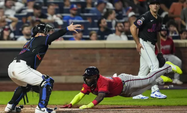 Atlanta Braves' Michael Harris II, bottom right, slides into home during the eighth inning of a baseball game against the New York Mets, Thursday, Aug. 14, 2025, in New York. (AP Photo/Yuki Iwamura)