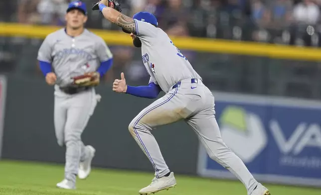 Toronto Blue Jays right fielder Nathan Lukes, right, pulls in a fly ball off the bat of Colorado Rockies' Thairo Estrada to end the fourth inning of a baseball game Monday, Aug. 4, 2025, in Denver. (AP Photo/David Zalubowski)