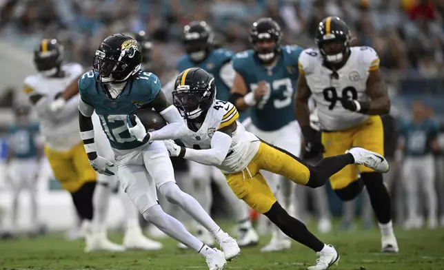 Jacksonville Jaguars wide receiver Travis Hunter (12) is tackled by Pittsburgh Steelers' James Pierre (42) during the first half of an NFL preseason football game, Saturday, Aug. 9, 2025, in Jacksonville, Fla. (AP Photo/Phelan M. Ebenhack)