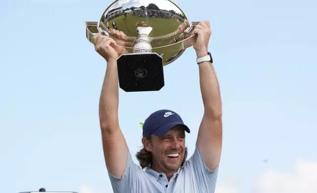 Tommy Fleetwood, of England, holds the championship trophy after the final round of the Tour Championship golf tournament, Sunday, Aug. 24, 2025, in Atlanta. (AP Photo/Mike Stewart)