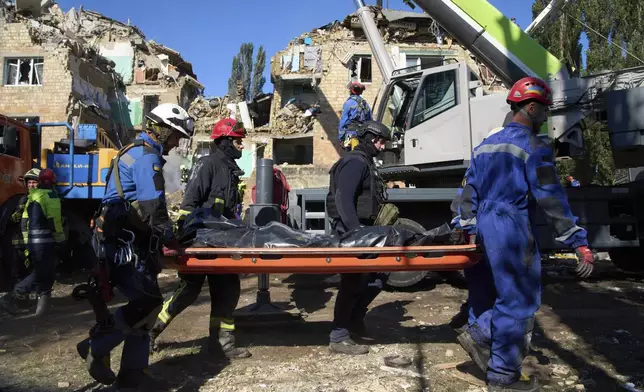 Firefighters carry a body in front of a damaged building after a Russian attack in Kyiv, Ukraine, Thursday, Aug. 28, 2025. (AP Photo/Efrem Lukatsky)