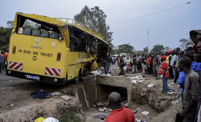 People gather at the scene of a bus accident that overturned, killing several people, in Kisumu, Kenya, Friday, Aug. 8, 2025. (AP Photo/Brian Ongoro)