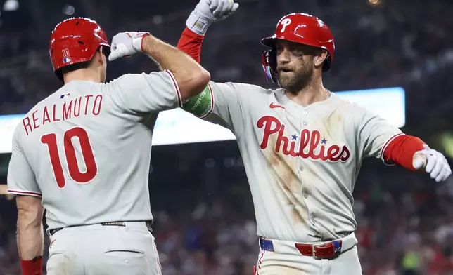 Philadelphia Phillies' Bryce Harper celebrates with Philadelphia Phillies' J.T. Realmuto after hitting a home run during the seventh inning of a baseball game against the Washington Nationals, Friday, Aug. 15, 2025, in Washington. (AP Photo/Daniel Kucin Jr.)