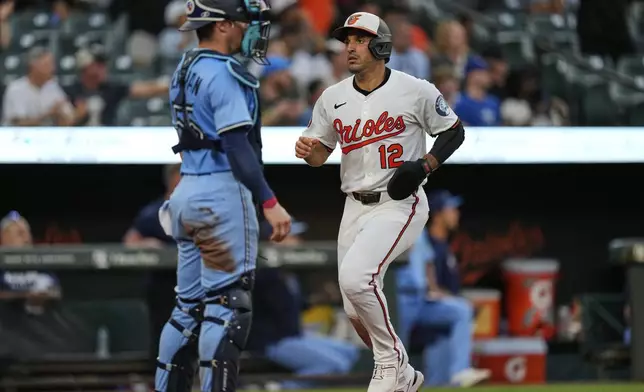 Baltimore Orioles' Ramon Laureano (12) scores past Toronto Blue Jays catcher Tyler Heineman, left, on an RBI triple hit by Ryan O'Hearn during the fourth inning in the second baseball game of a doubleheader, Tuesday, July 29, 2025, in Baltimore. (AP Photo/Stephanie Scarbrough)