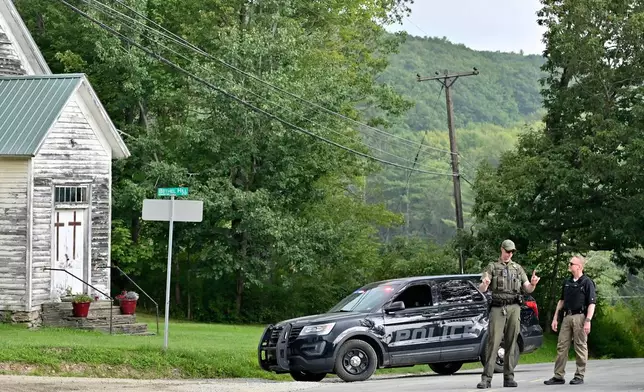 Police officers block the street leading to where two Pennsylvania state troopers were ambushed and shot Thursday, Aug. 7, 2025, near the village of Thompson, in Susquehanna County, Pa. (AP Photo/Aimee Dilger)