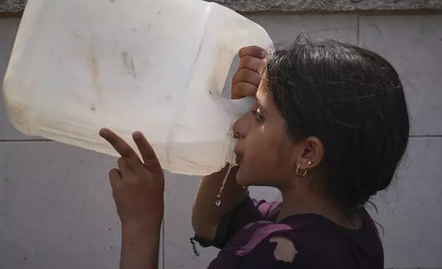 A Palestinian girl drinks water from a jerrycan after collecting it from a water distribution point during a hot summer day with temperatures reaching 36 °C (97 °F) in Deir al-Balah, in the central Gaza Strip, Wednesday, Aug. 13, 2025. (AP Photo/Abdel Kareem Hana)