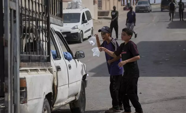 Palestinian children sell bags of drinking water during a hot summer day with temperatures reaching 36 °C (97 °F) in Deir al-Balah, central Gaza Strip, Wednesday, Aug, 13, 2025. (AP Photo/Abdel Kareem Hana)