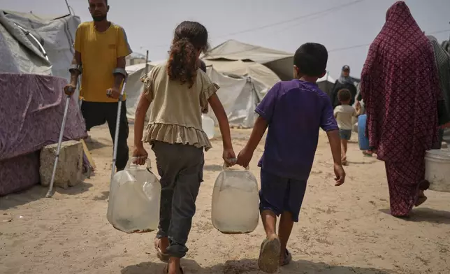 In the summer heat, Palestinian children carry jerrycans after collecting water from a distribution point in Gaza City, Tuesday, Aug. 12, 2025. (AP Photo/Jehad Alshrafi)