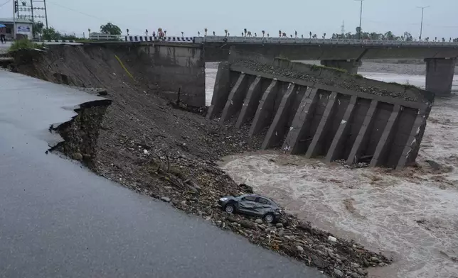 People looks at the damaged bridge over the swelling Tawi River in Jammu, India, Wednesday, Aug. 27, 2025. (AP Photo/Channi Anand)