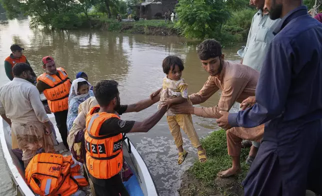 A rescue worker helps villagers evacuated from a flooded area of Chango Walia village, in Narowal district, Pakistan, Wednesday, Aug. 27, 2025. (AP Photo/K.M. Chaudary)