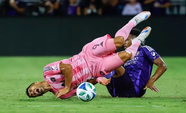 Orlando City defender Alex Freeman, right, slides into Inter Miami forward Luis Suárez (9) during the first half of an MLS soccer match Sunday, Aug. 10, 2025, in Orlando, Fla. (AP Photo/Kevin Kolczynski)