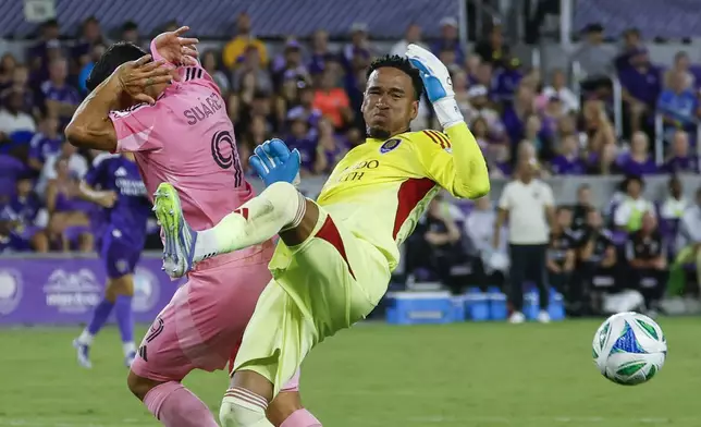 Orlando City goalkeeper Pedro Gallese, right, and Inter Miami forward Luis Suárez, left, go for the ball during the first half of an MLS soccer match, Sunday, Aug. 10, 2025, in Orlando, Fla. (AP Photo/Kevin Kolczynski)