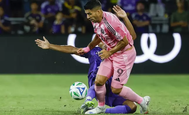 Orlando City defender Alex Freeman, left, slides into Inter Miami forward Luis Suárez (9) during the first half of an MLS soccer match, Sunday, Aug. 10, 2025, in Orlando, Fla. (AP Photo/Kevin Kolczynski)
