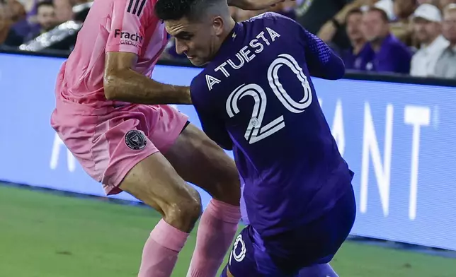 Orlando City midfielder Eduard Atuesta (20) and Inter Miami midfielder Sergio Busquets fight over the ball during the first half of an MLS soccer match, Sunday, Aug. 10, 2025, in Orlando, Fla. (AP Photo/Kevin Kolczynski)