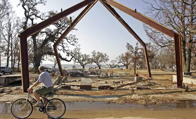 FILE - A cyclist rides by the remains of the Episcopal Church of the Redeemer while ministers conduct religious services on the beach in Gulfport, Miss., on Sept. 11, 2005. (AP Photo/Rob Carr, File)
